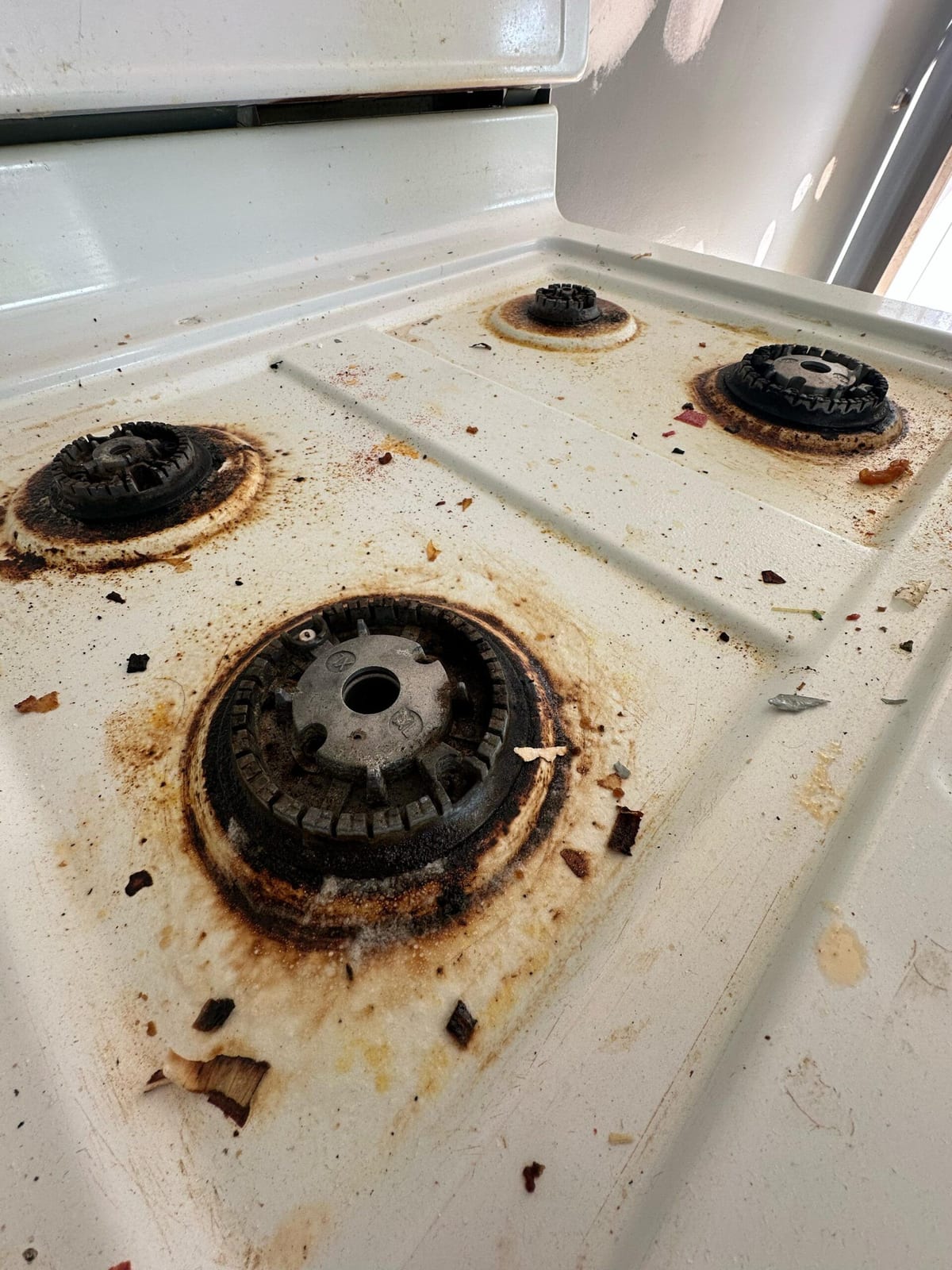 A gas range with burnt-on residue around the burners before deep cleaning