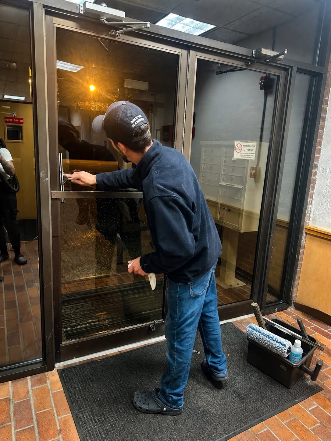 A team member cleaning the glass entrance doors of an office building