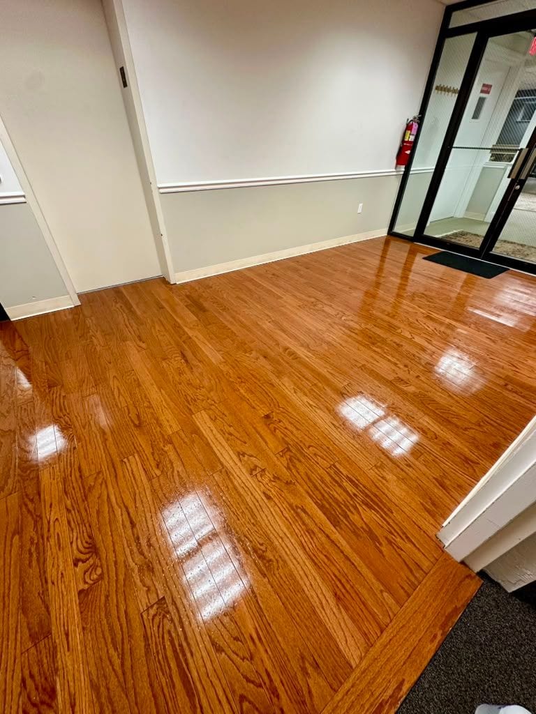 A polished hardwood lobby floor beside the glass entrance doors of a commercial building