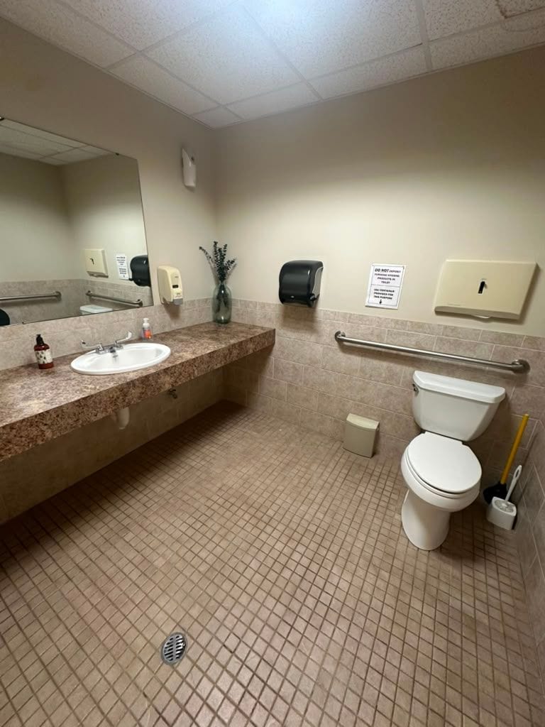 An office building restroom with vanity and accessible grab bars after cleaning