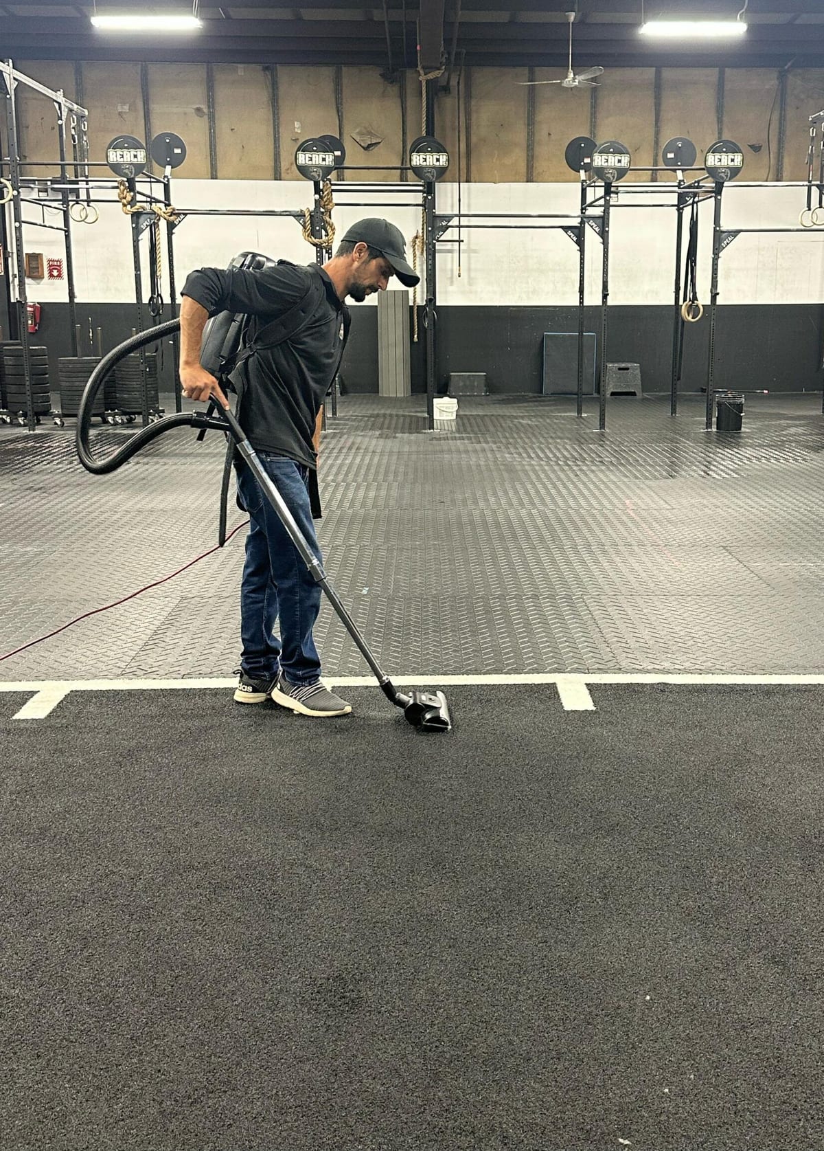 A Cupertino's team member vacuuming the training floor of a local fitness facility