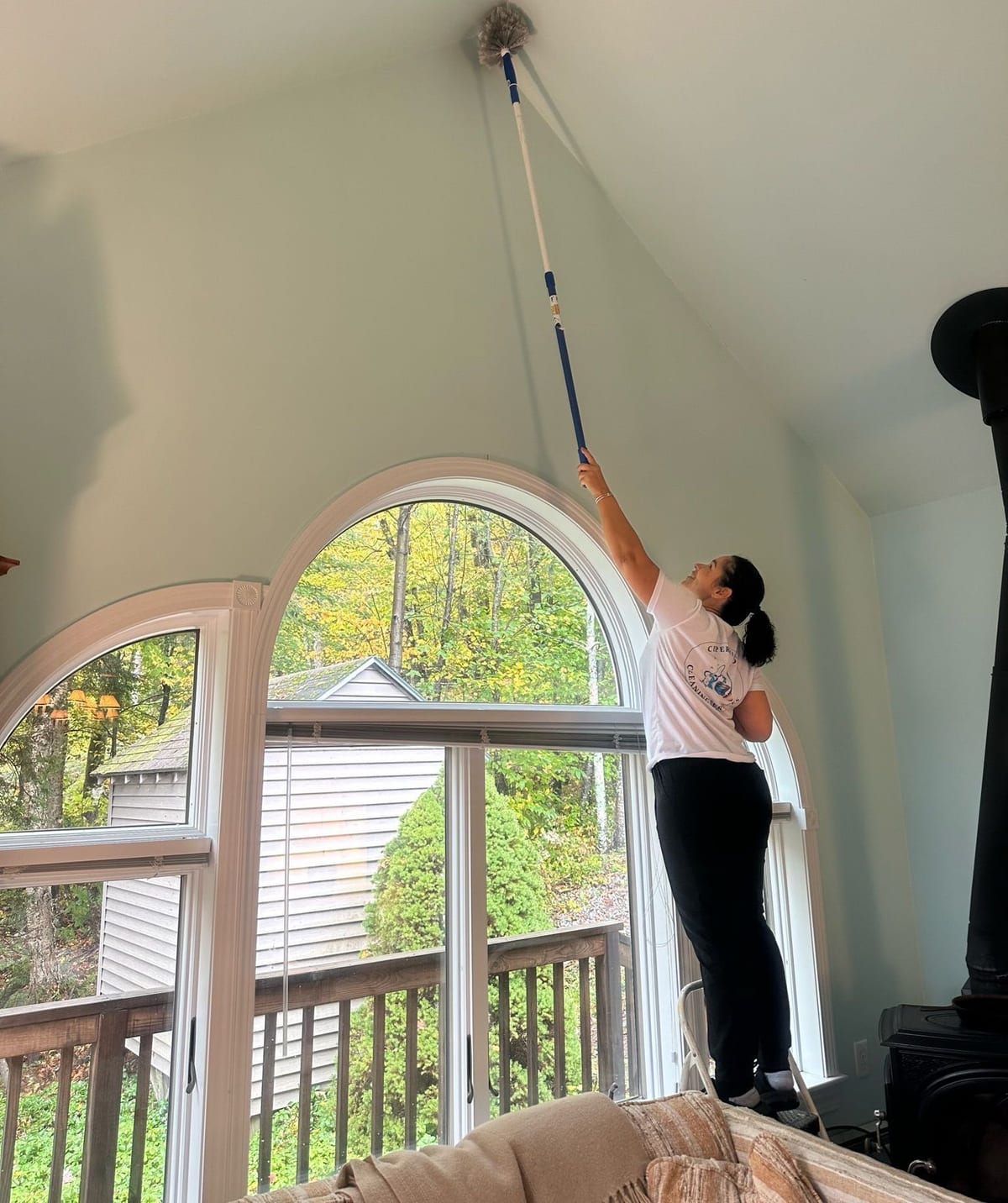 A Cupertino's team member using an extension pole to clean a tall arched window