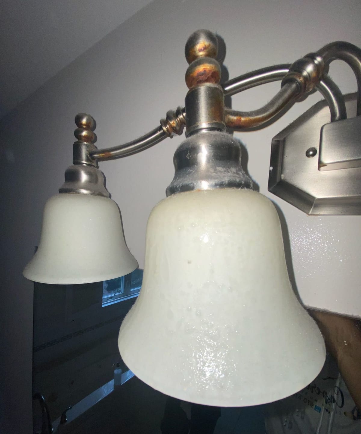 A cleaned vanity light fixture above a bathroom mirror