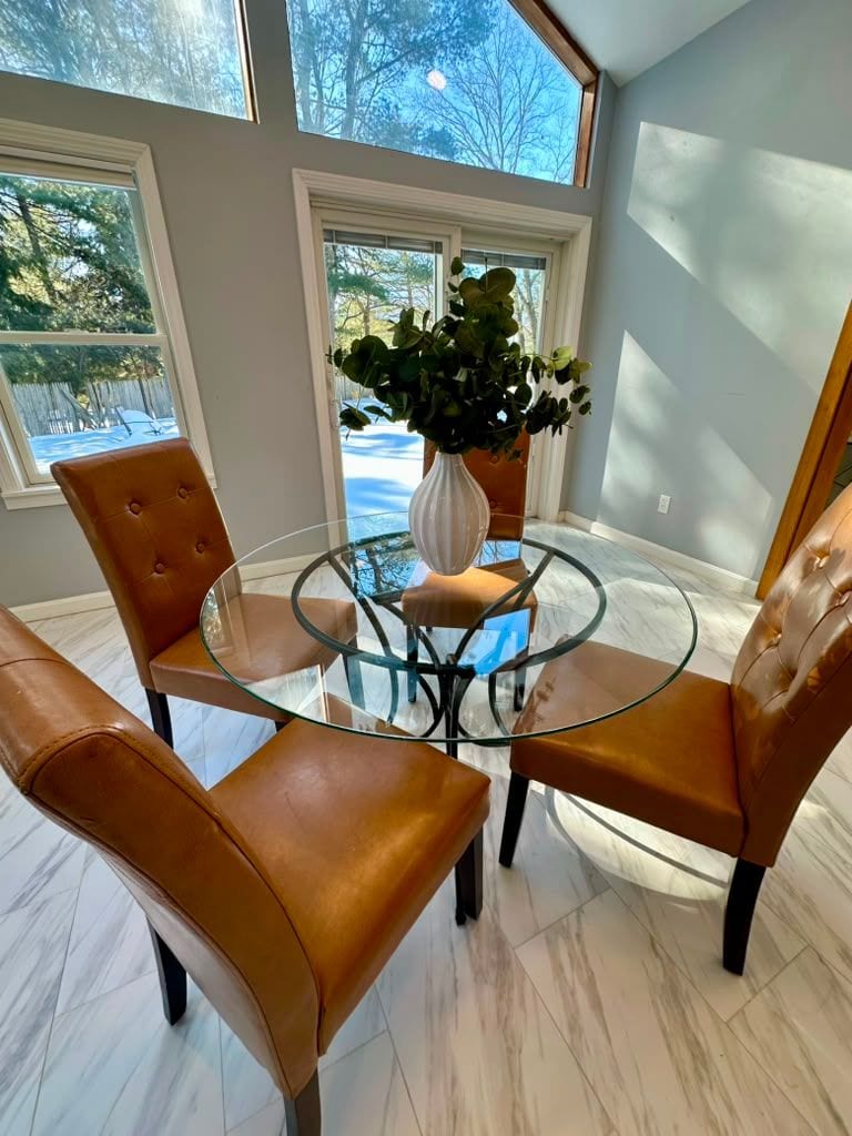 A glass dining table and leather chairs by tall windows after a cleaning