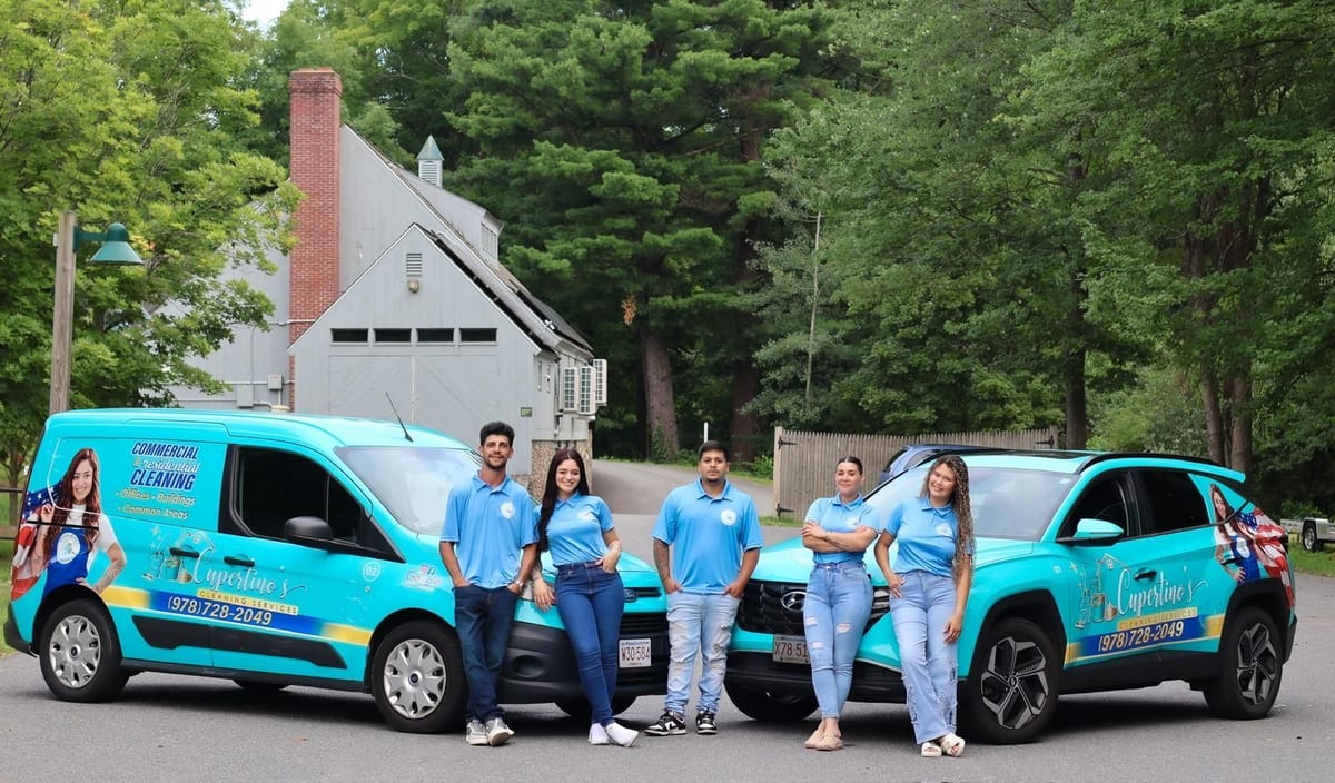 The Cupertino's Cleaning Services team in front of two branded vehicles