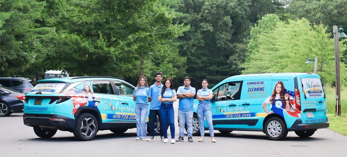 The full Cupertino's Cleaning Services team standing between two branded vehicles